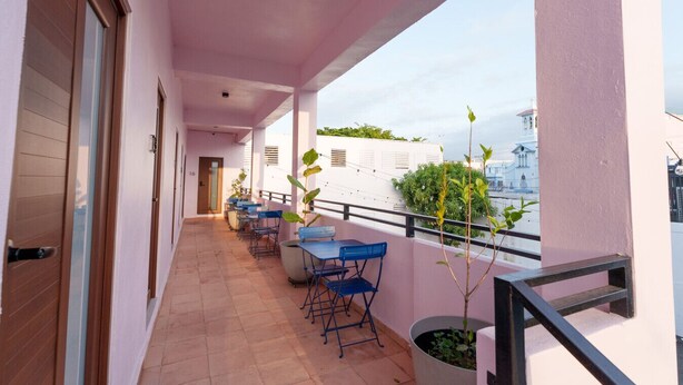 A balcony with a tiled floor, a row of blue chairs, and potted plants. - Compact Bunk Room in Arts District + Free Parking (San Juan)