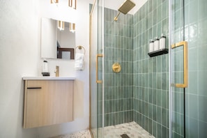 Un baño moderno con ducha, lavamanos y espejo.