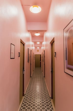 Un pasillo con paredes rosas, baldosas de suelo estampadas y puertas numeradas 2 y 3.
