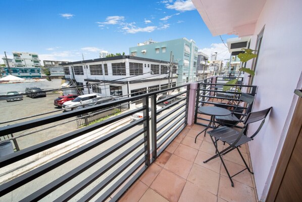 A balcony with a view of a parking lot and buildings.