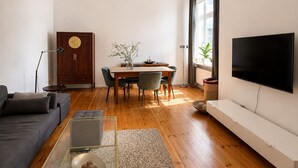 Una sala moderna con un sofá, una mesa de comedor con sillas, un televisor y un mueble de madera.