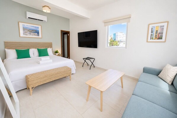 Una habitación de hotel moderna con cama, sofá, una mesita y televisor.