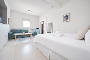 Una habitación de hotel moderna con una cama grande, un sofá, una mesita y un microondas.