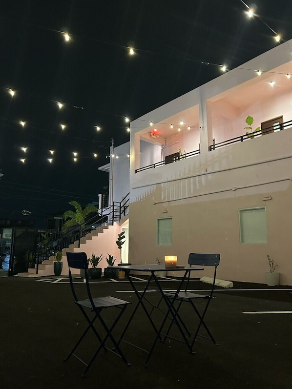 Ein modernes Gebäude mit Balkon, Sitzgelegenheiten im Freien und Lichterketten.