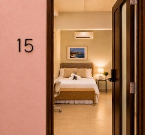 Habitación de hotel con cama, mesita de noche, lámpara y un cuadro en la pared.