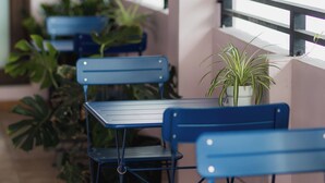 A seating area with blue tables and chairs, potted plants, and a balcony railing. - Skyline Sips and Santurce Charm (San Juan)