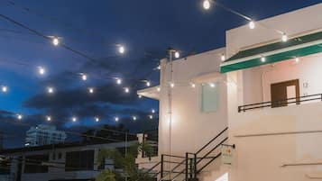 Un bâtiment doté d’un escalier menant à un étage supérieur, d’une signalétique indiquant les numéros des pièces et d’une guirlande lumineuse décorative à l’extérieur.