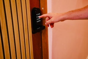 A hand pressing a numeric keypad on a door lock.