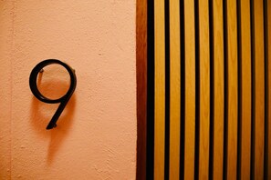 Un número nueve sobre una pared con textura y un panel de madera con listones verticales.