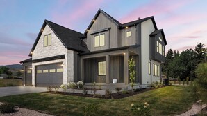 A modern two-story house with a stone facade, large windows, and a well-maintained lawn.