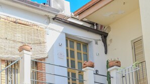Un immeuble de deux étages doté d’un balcon, d’une fenêtre avec un volet et d’une porte avec une plaque numérotée.