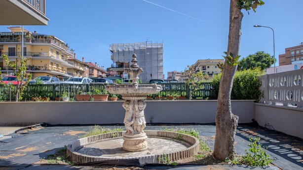 A courtyard with a central fountain, surrounded by a low wall and potted plants. - Magnolia House - Appartamento 1 (Tor Lupara)