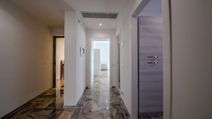 A hallway with a marble floor, white walls, and a wooden door. - Magnolia House - Appartamento 1 (Tor Lupara)