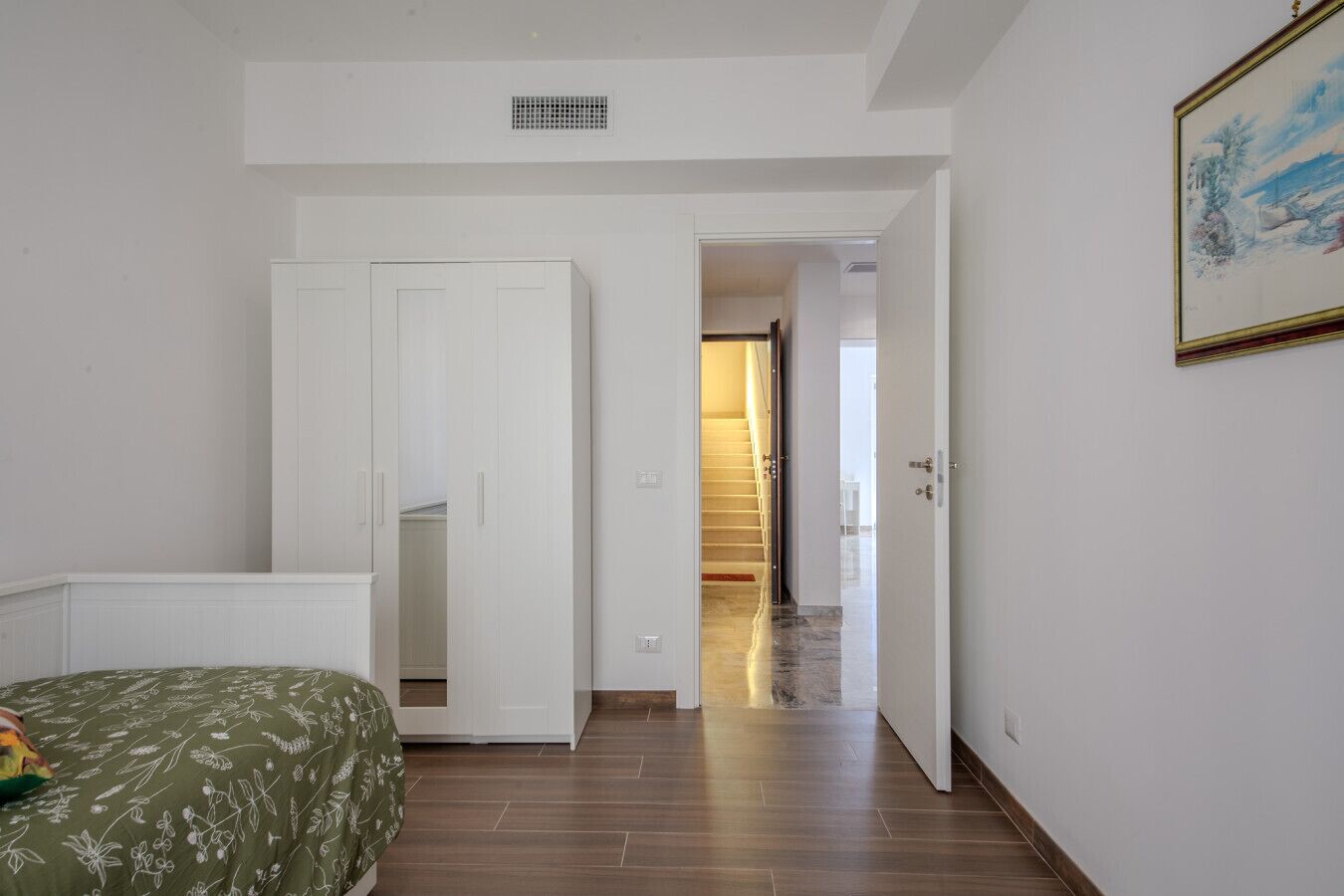 Ein Schlafzimmer mit Bett, Kleiderschrank und einer Treppe zu einem anderen Raum.