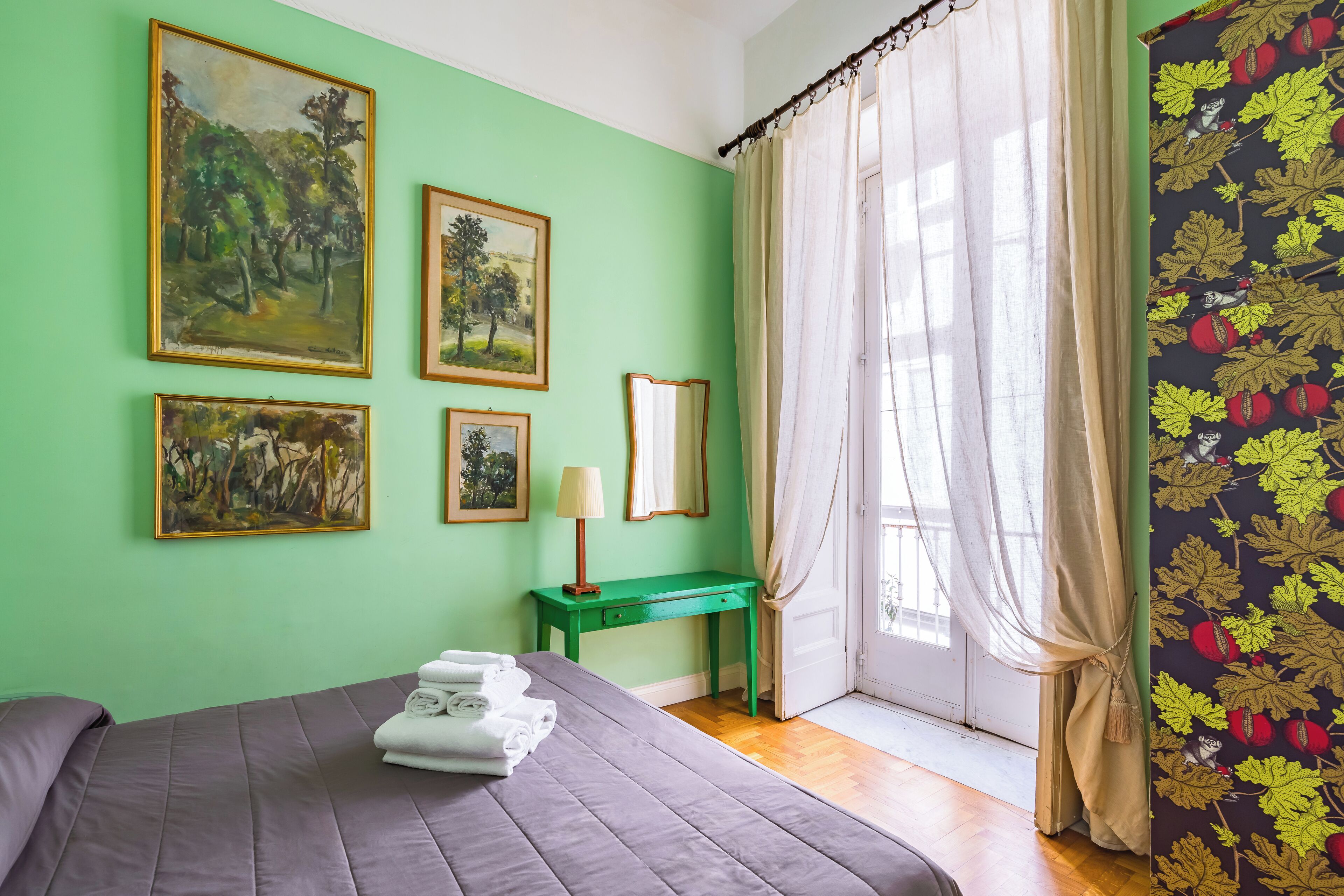 A room with a bed, green walls, and artwork.