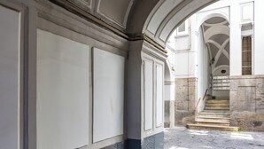 Un corredor arqueado con suelo de piedra y paredes blancas.