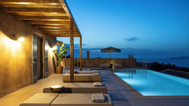 A poolside area with lounge chairs and a view of the sea. - Terracotta Fiscrdo Villas
 3 bedrooms (Fiscardo)