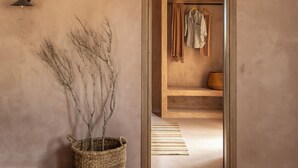 A room with a neutral-toned wall, a woven basket with branches, a hanging coat rack, and a wooden bench. - Terracotta Fiscrdo Villas
 3 bedrooms (Fiscardo)