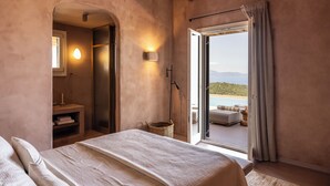 A bedroom with a large bed, a view of the outdoors, and a small seating area. - Terracotta Fiscrdo Villas
 3 bedrooms (Fiscardo)