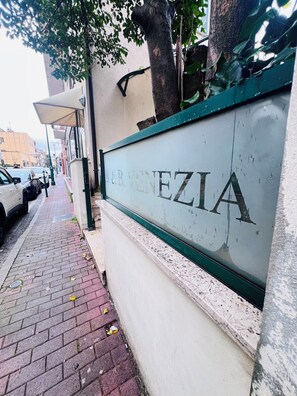 A sign for "A&B VENEZIA" with a brick sidewalk and parked cars. - L'affito Camera di Venezia (Mestre)