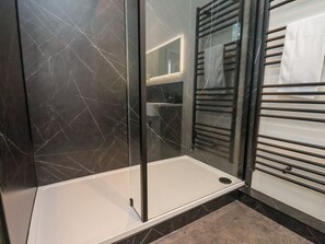 Ein modernes Badezimmer mit Duschkabine aus Glas, einer weißen Badewanne und einem Handtuchhalter.
