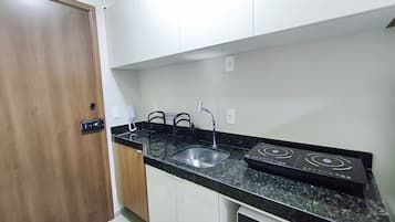 A compact kitchen with a sink, a stove, and a door.