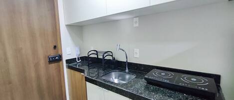 A compact kitchen with a sink, a stove, and a door.