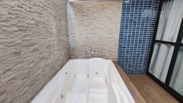Um banheiro moderno com parede de pedra, área de chuveiro com azulejos azuis e uma banheira grande.