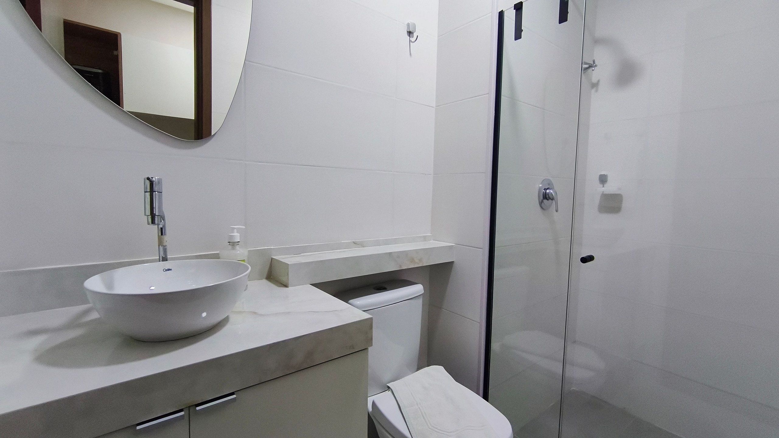 A modern bathroom with a vessel sink, a mirror, a toilet, and a glass shower enclosure.
