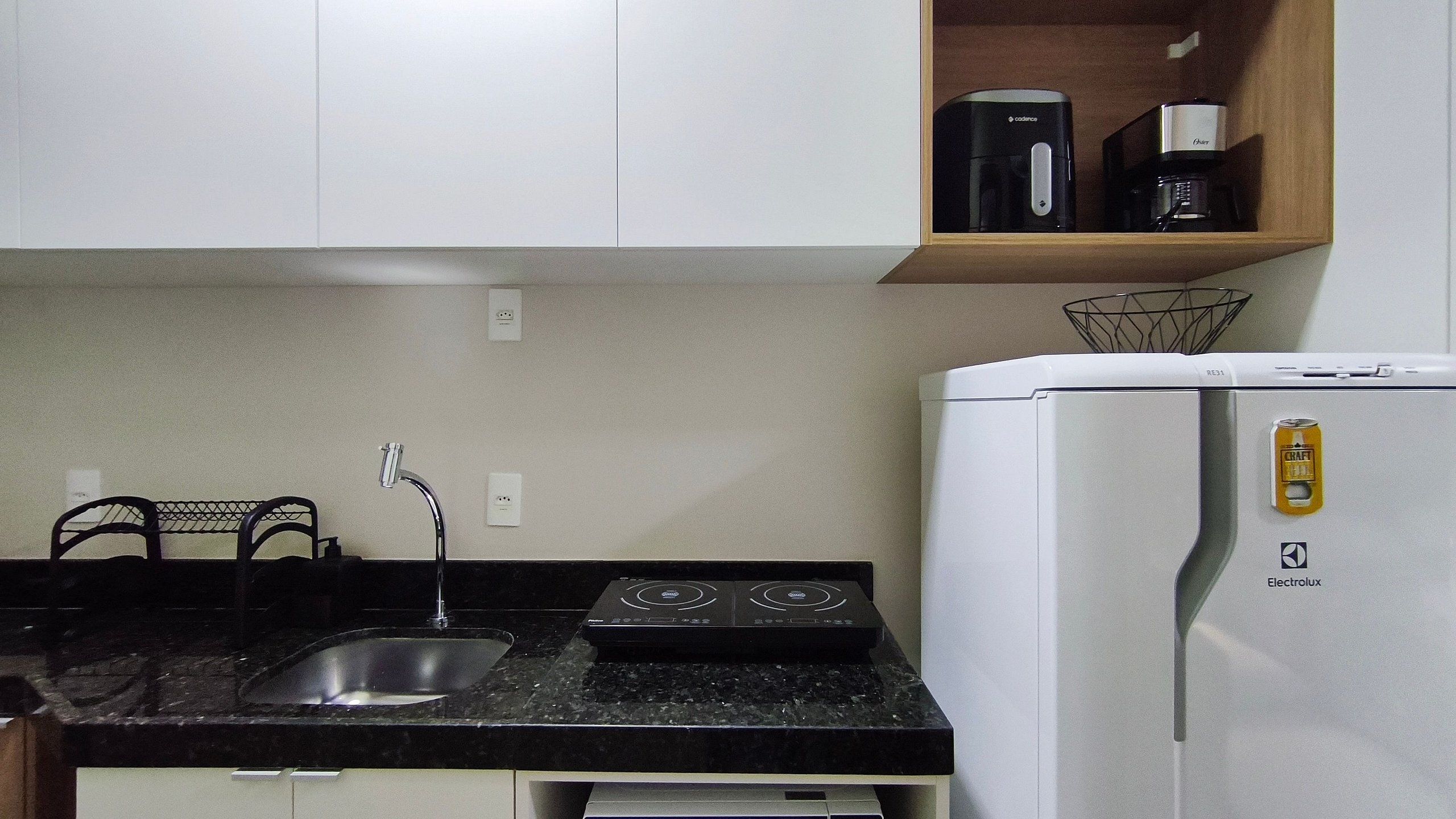 A kitchen with a sink, stove, and a white refrigerator with a can magnet.