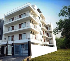 A multi-story residential building with balconies, a gated entrance, and a well-maintained lawn.