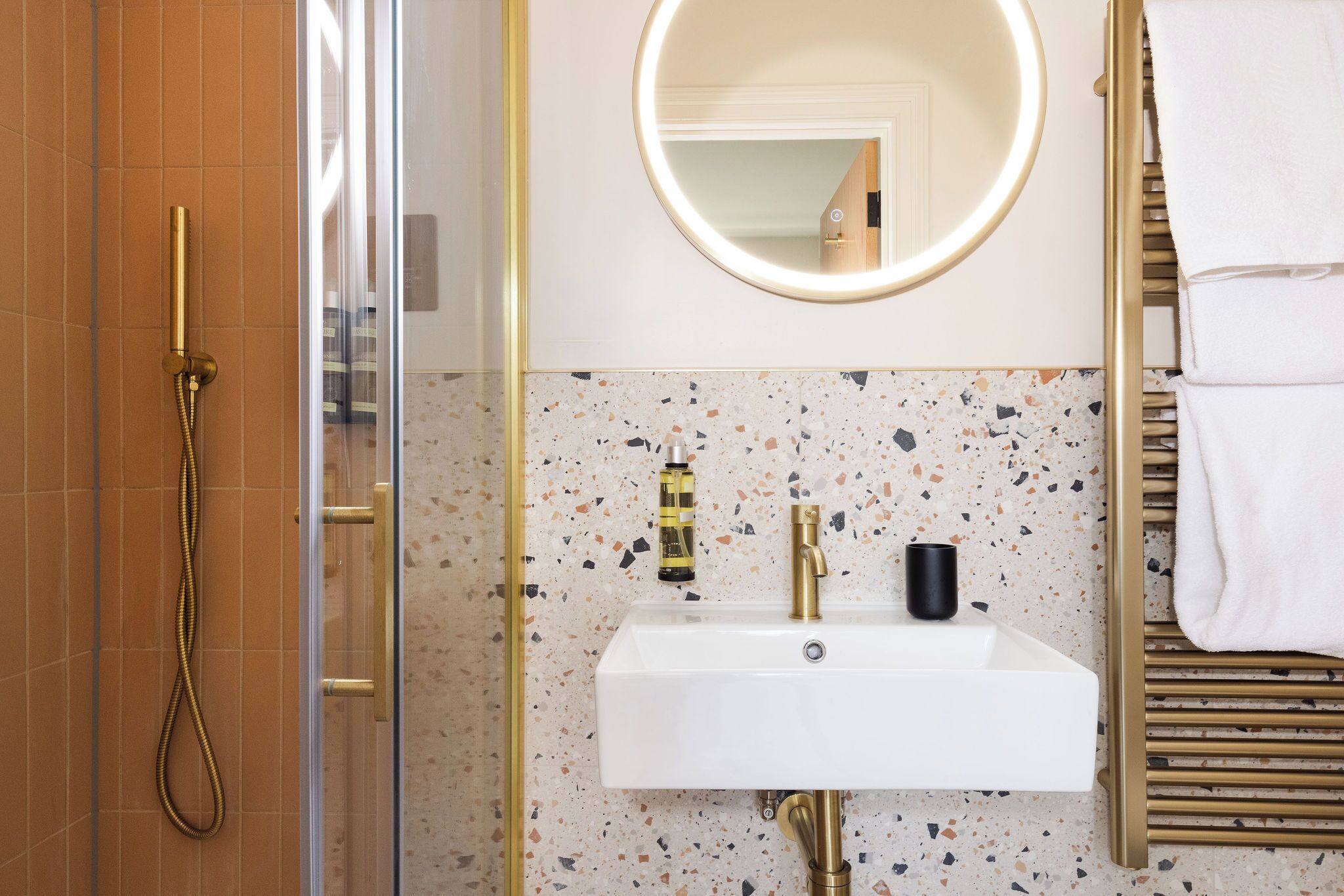 A bathroom with a shower, a sink with a mirror, and a towel rack.