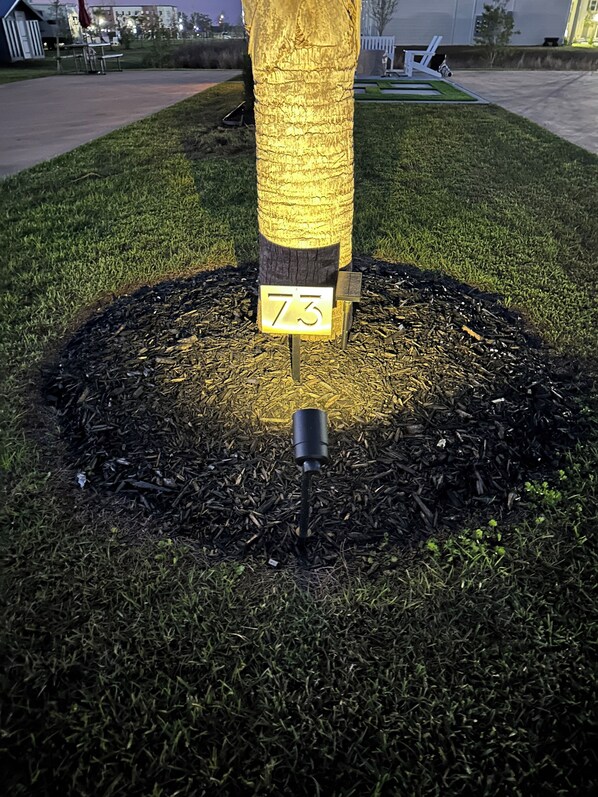 A tree with a number plaque '73' on a grassy area with mulch. - Premium RV Site 73 - Gated, Heated Pool & Near OWA (Foley)