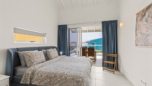 Ein Schlafzimmer mit Bett, einem kleinen Tisch, einem Stuhl und Blick ins Freie.