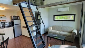 Un loft spacieux avec un escalier en bois, un coin cuisine, un canapé et un espace repas.