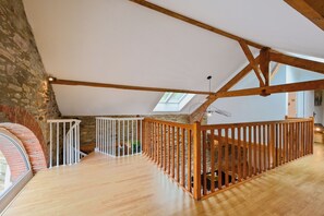 Un loft amplio con vigas de madera a la vista, una pared de piedra y un tragaluz.