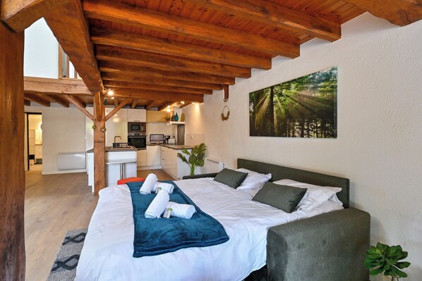 Un dormitorio con cama, escritorio, silla y un cuadro en la pared.