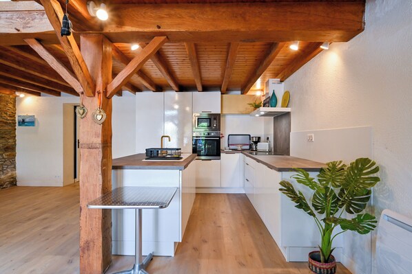 Una cocina moderna con vigas de madera, muebles blancos y una isla central.