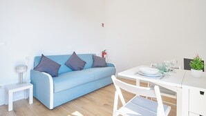 Una sala de estar moderna con un sofá azul, una mesa blanca y una mesita auxiliar.