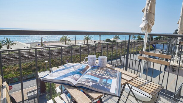 Un balcón con vista al mar, una revista y dos tazas.