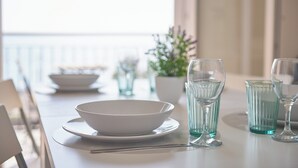Una mesa para comer con un tazón blanco, dos vasos transparentes y una botella de agua.