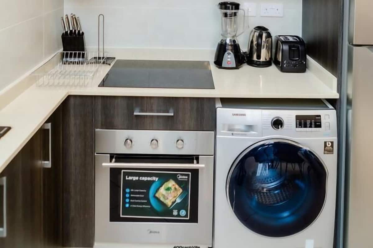 A compact kitchen with a microwave, toaster, blender, and washing machine.