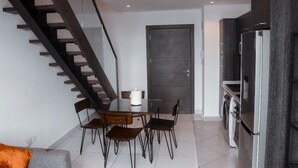 A modern kitchen with a built-in refrigerator, a dining area with a table and chairs, and a staircase leading to an upper level. - PREMIUM SUITE (Accra)