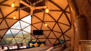 Un cuarto circular y acogedor con cama, almohadas y televisor.