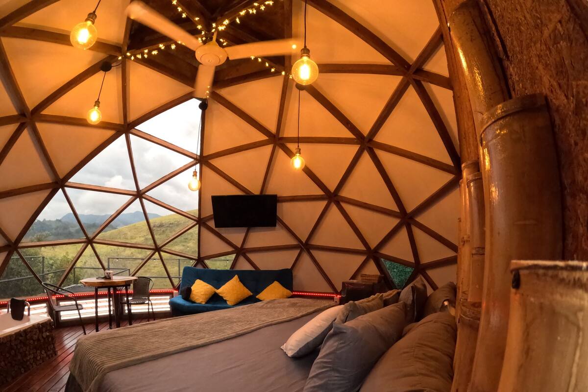 A cozy, circular room with a bed, pillows, and a TV.