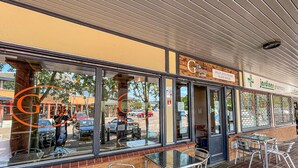 A restaurant with outdoor seating, a visible menu board, and a pharmacy across the street.