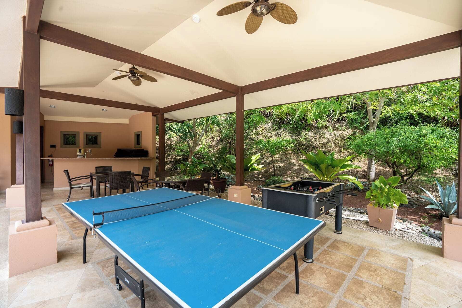 Un espacio al aire libre cubierto con mesa de ping pong, asientos y una parrilla.