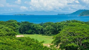 Üppige grüne Landschaft mit Golfplatz und Blick auf das Meer und vorgelagerte Inseln.