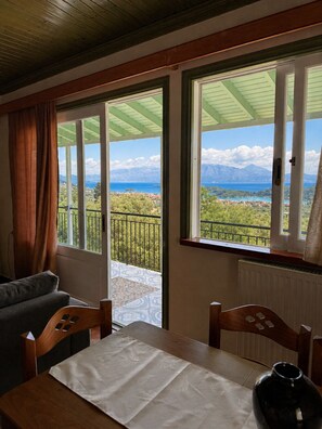 Une chambre avec balcon, une table recouverte d’une nappe blanche et une vue sur un paysage montagneux.