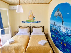A room with two beds, a mural of a dolphin, and a Tesla air conditioner.